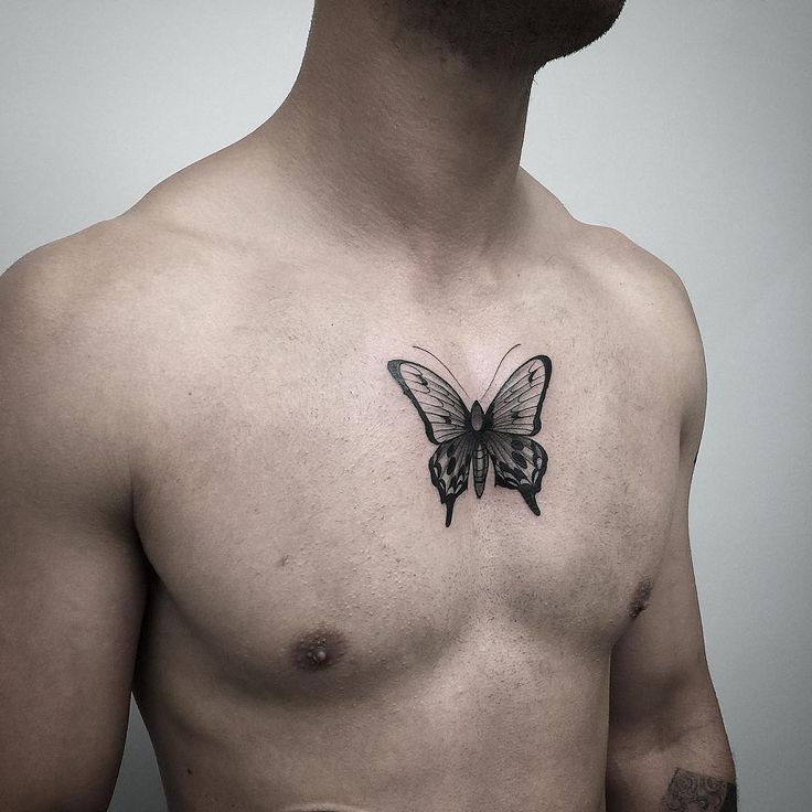 medium-sized black and grey tattoo on man's chest of realistic butterfly