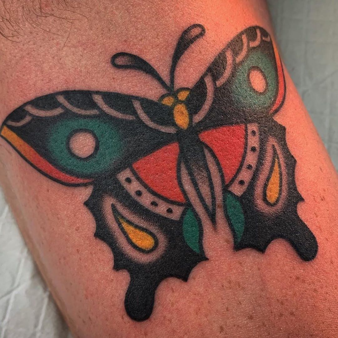 medium-sized traditional color tattoo on man's lower leg of a teal orange butterfly