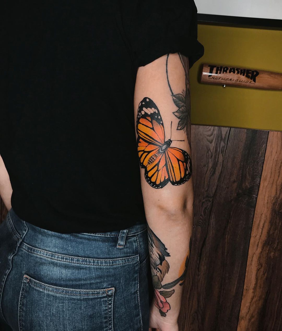 large color tattoo on woman's forearm of realistic orange monarch butterfly