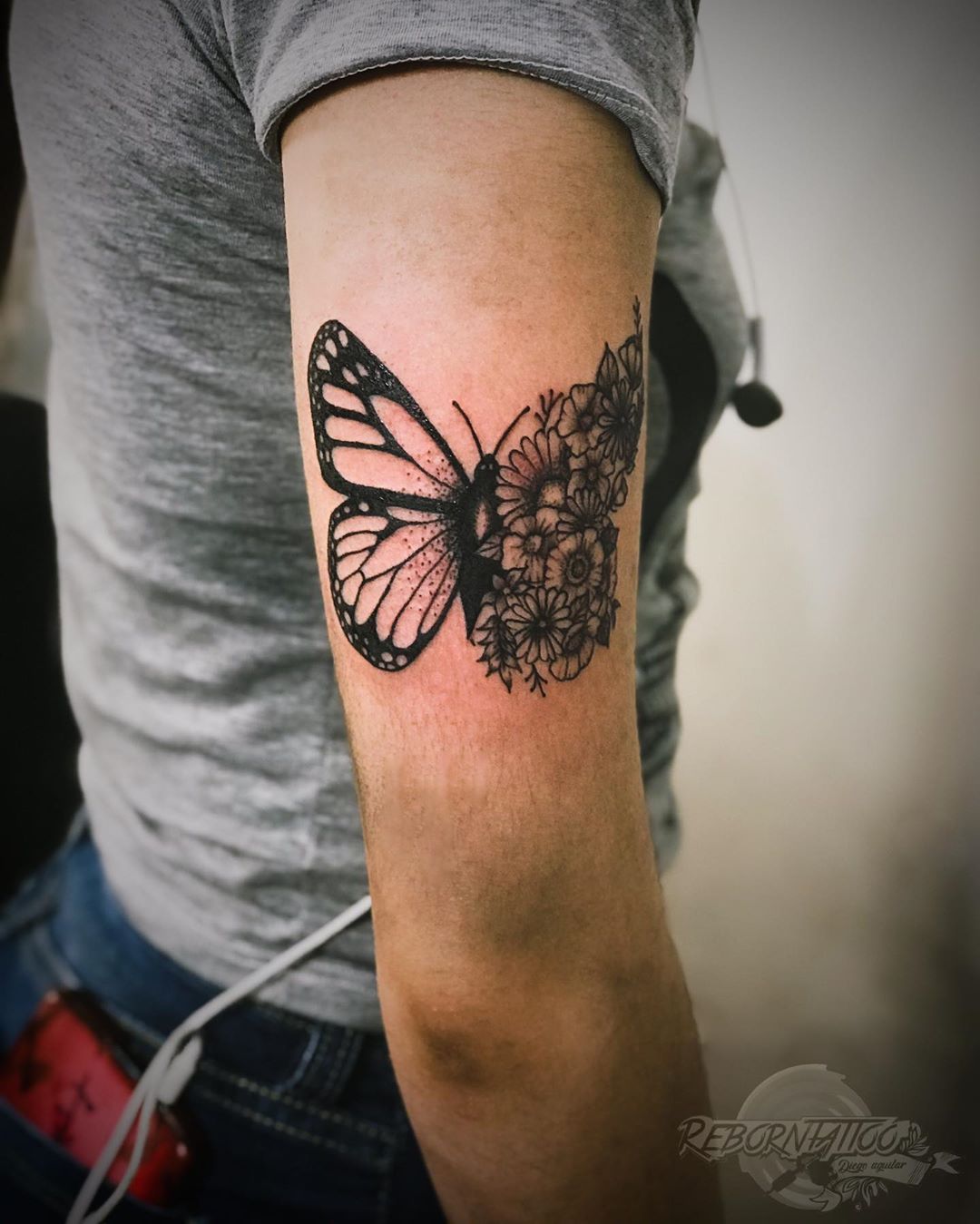 medium-sized black and grey tattoo on woman's upper arm of butterfly with one floral wing