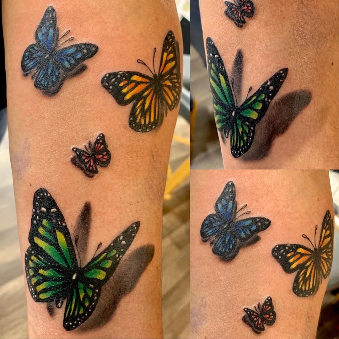 large color tattoos on a woman's lower leg of multiple realistic butterflies with shadows