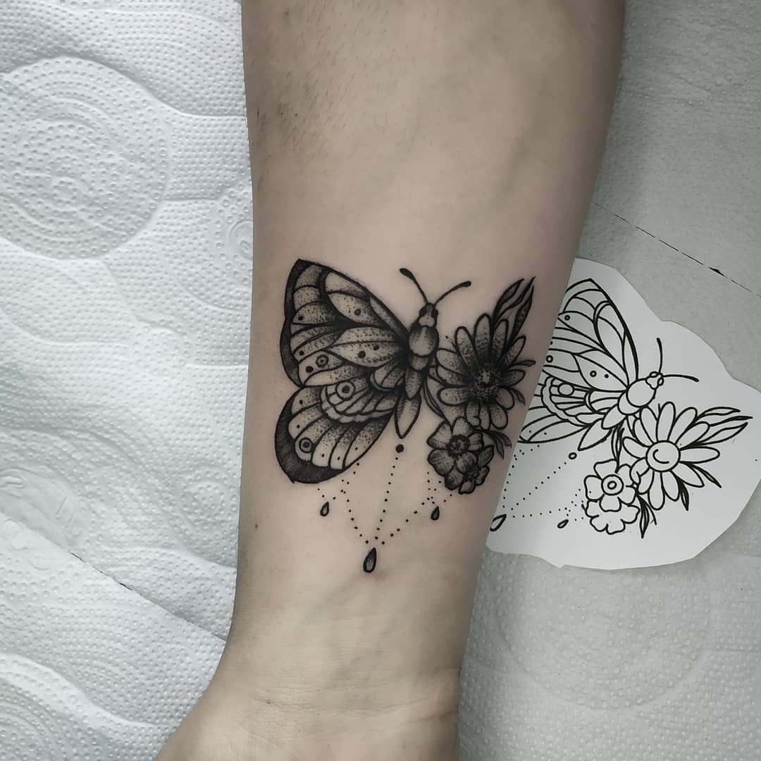 medium-sized black and grey tattoo on forearm near wrist of a surrealistic butterfly with one floral wing