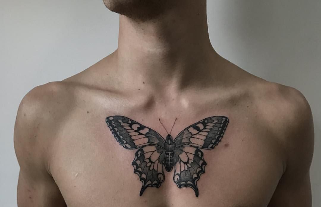 large black and grey tattoo on man's chest of a realistic butterfly
