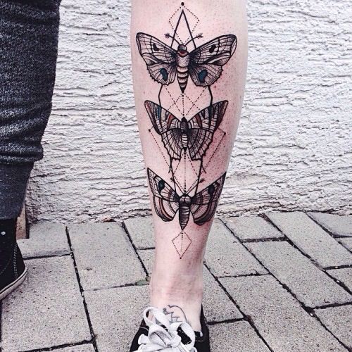large black and color tattoo on thigh of a butterfly with red geometric lines and shapes behind it