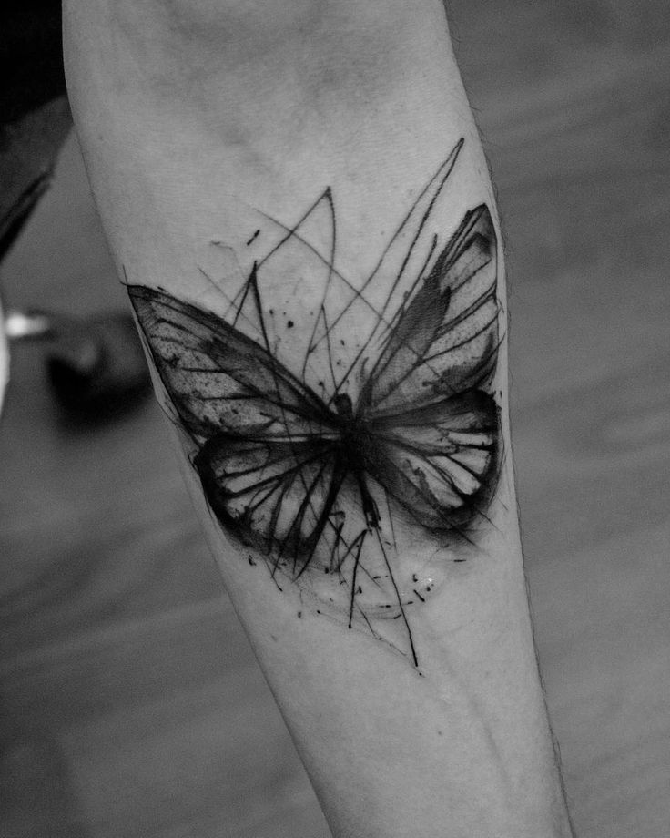 medium-sized black and grey geometric tattoo on man's forearm of surrealistic butterfly with messy lines around it